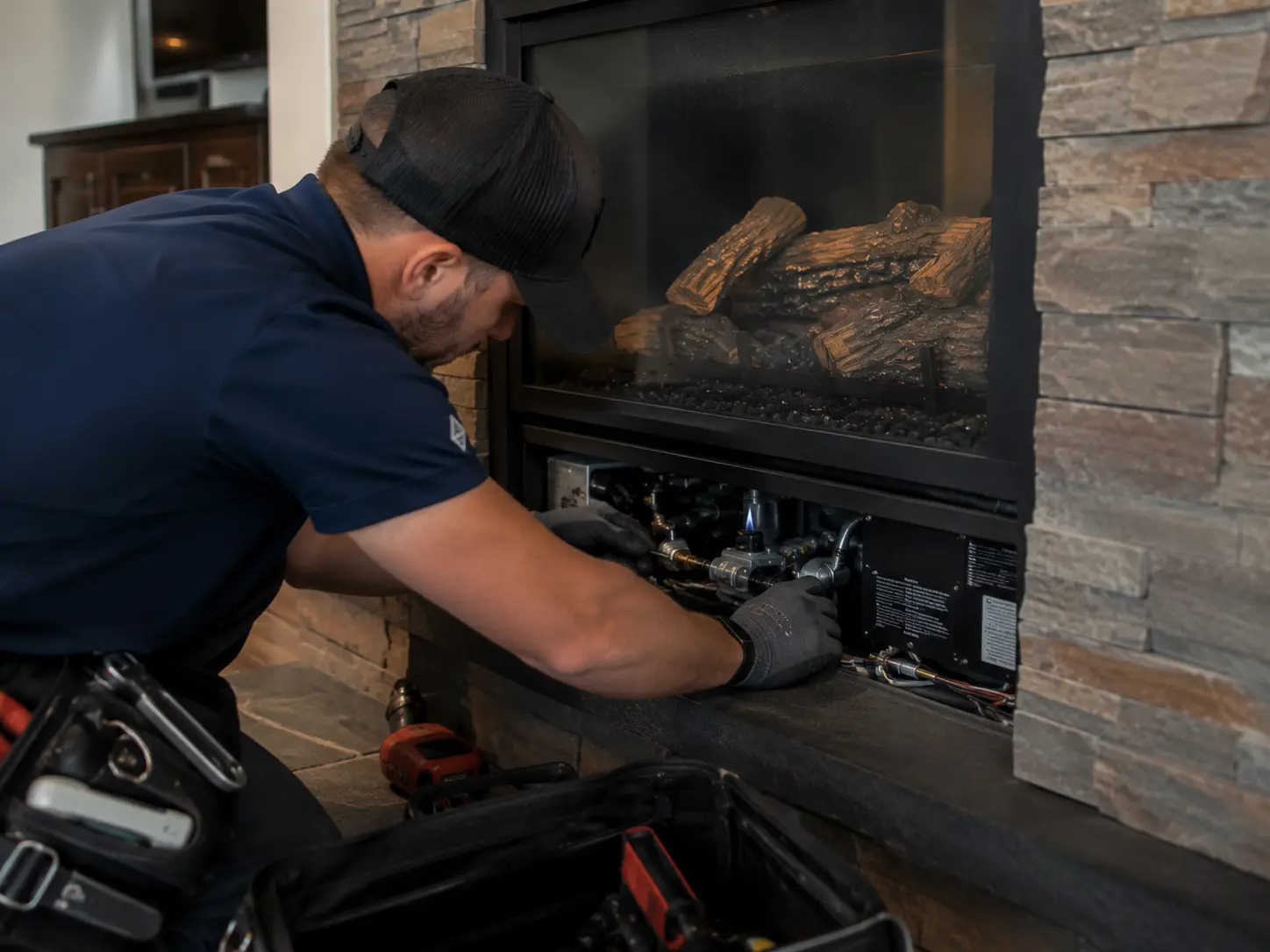 Professional checking pilot and ignition components inside a gas fireplace